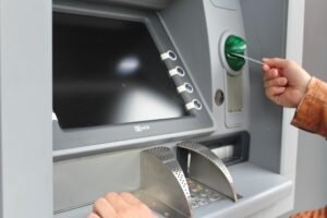 Person using an ATM with card slot, keypad and screen, representing banking access in Kalkan.