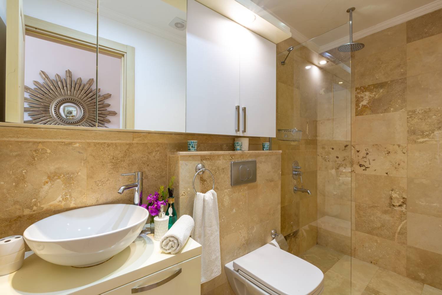 Modern bathroom at Kalkan Limon Apartment with marble tiles, vessel sink and glass‑enclosed shower.