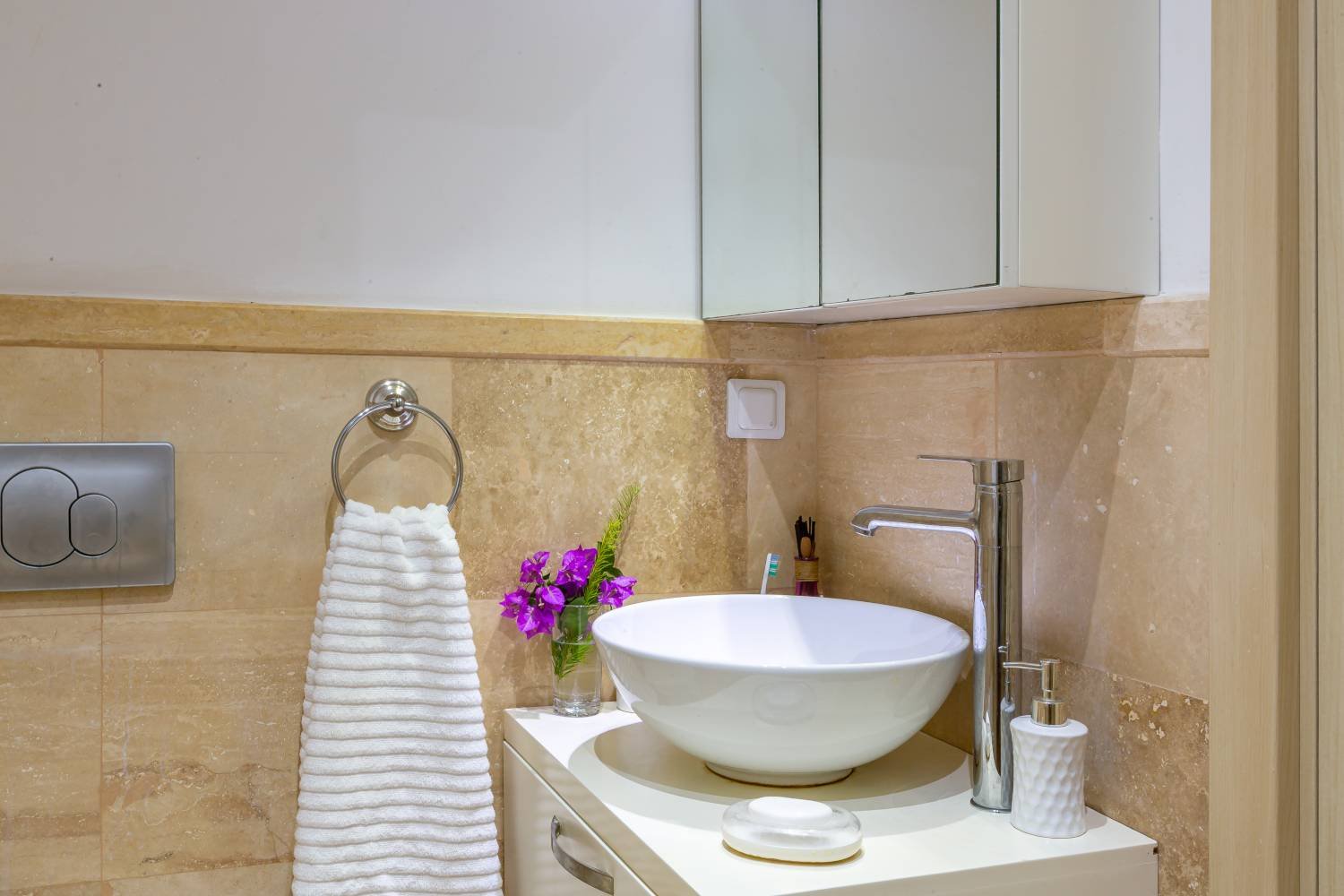 Modern bathroom sink at Kalkan Limon Apartment with marble tiles, round basin and decorative accessories.