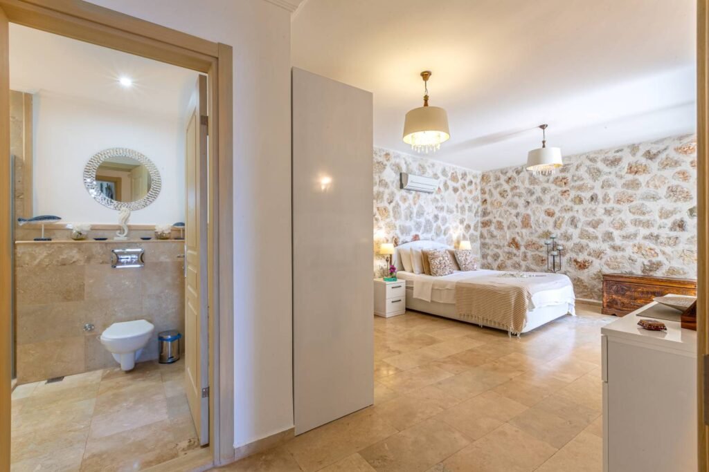 Bathroom at Kalkan Limon Apartment with marble tiles, wall‑mounted toilet and decorative mirror.