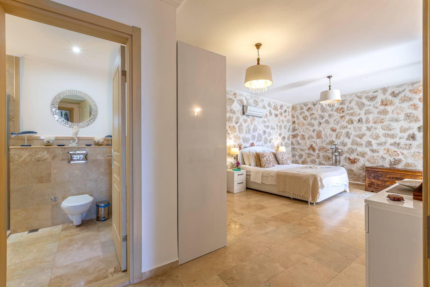 Bathroom at Kalkan Limon Apartment with marble tiles, wall‑mounted toilet and decorative mirror.