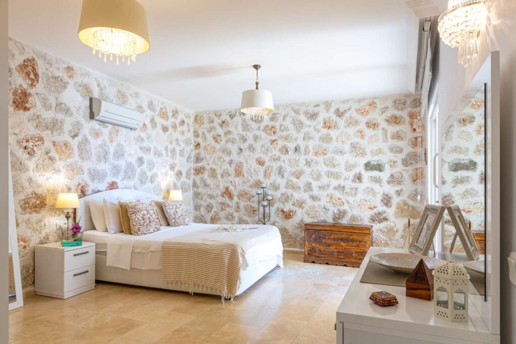 Elegant bedroom at Kalkan Limon Apartment with stone‑patterned walls, double bed and decorative furnishings.