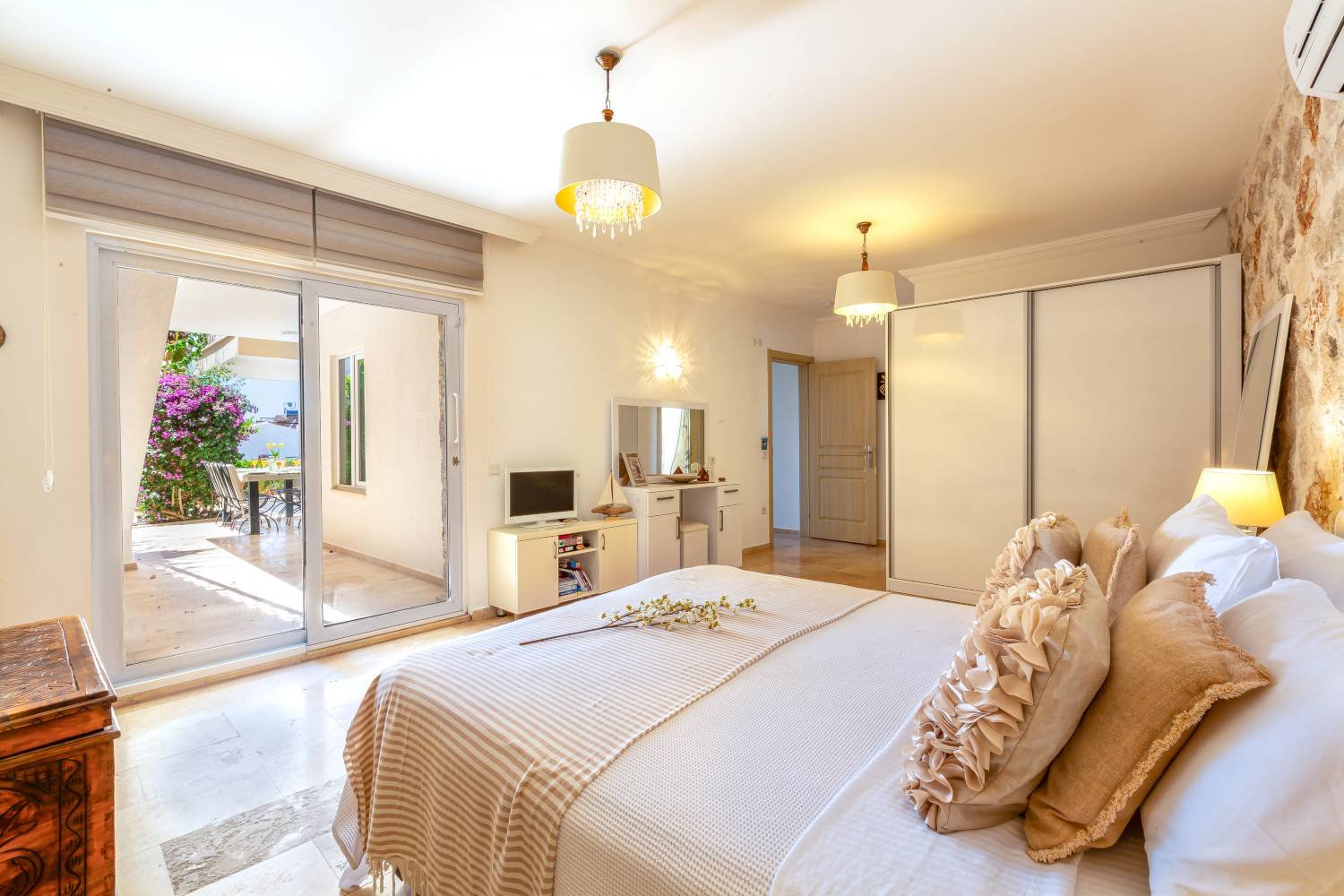 Bright double bedroom at Kalkan Limon Apartment with stone‑patterned walls, modern lighting and decorative furnishings.