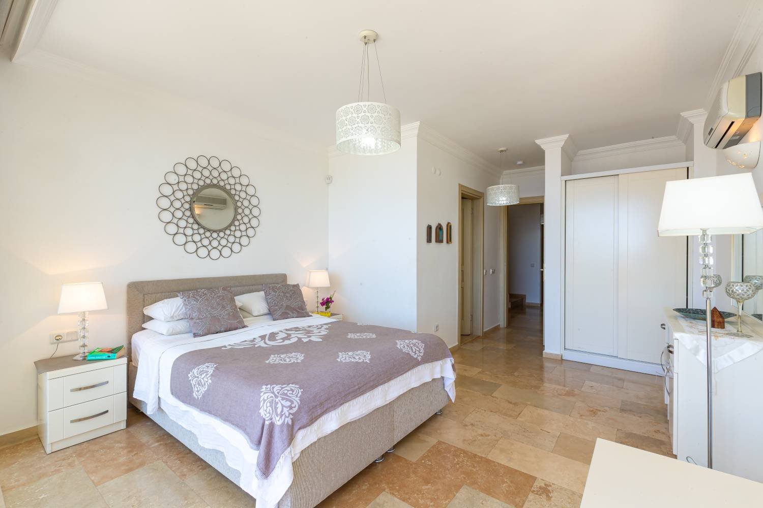 Modern double bedroom at Kalkan Limon Apartment with grey headboard, white bedding and decorative mirror.