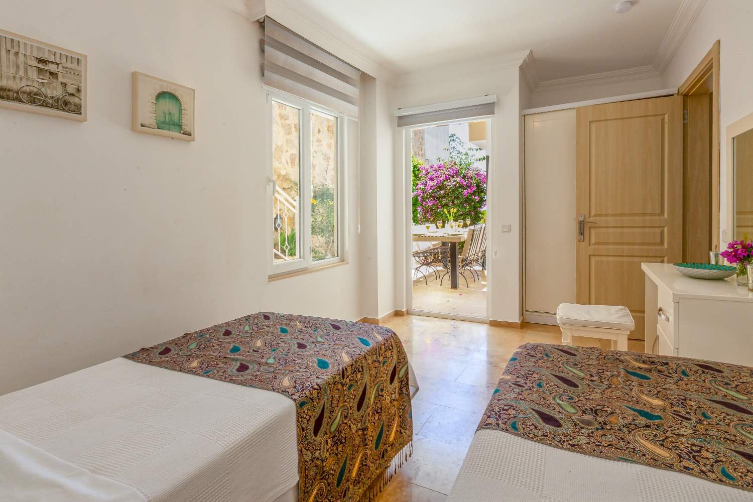 Bright twin bedroom at Kalkan Limon Apartment with two single beds, paisley bedspreads and terrace access.