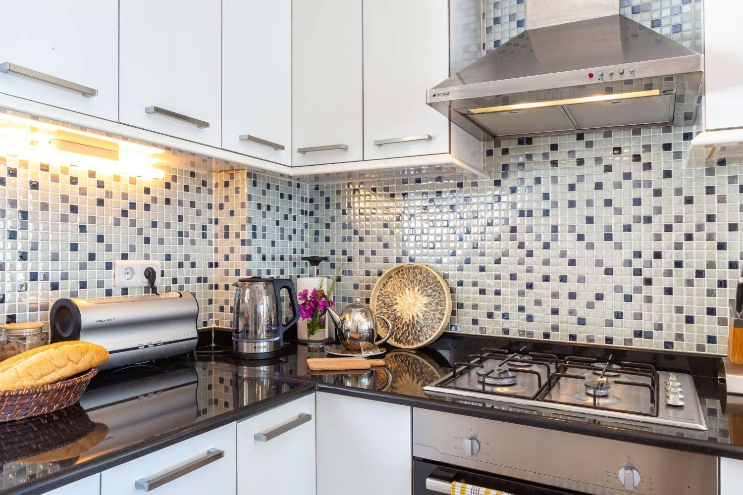 Modern kitchen corner at Kalkan Limon Apartment with mosaic backsplash, stainless appliances and decorative countertop items.