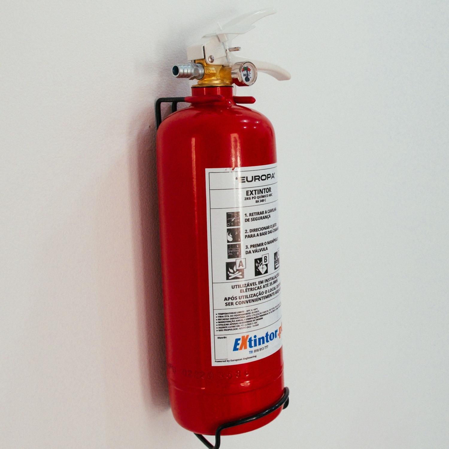 Red fire extinguisher mounted on a white wall at Kalkan Limon Apartment.