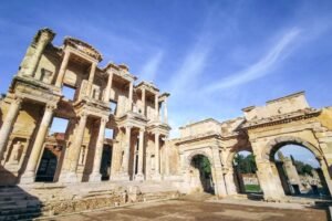 Ancient façade of the Library of Celsus in Ephesus with ornate columns and stone archway under a clear sky.
