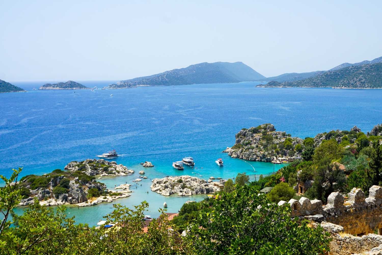 Turquoise bay at Kekova with boats, rocky islands and ancient coastal ruins near Kalkan.