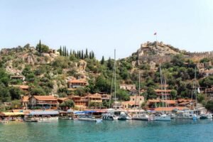 Kekova hillside village with fortress, turquoise waterfront and boats near Kalkan.