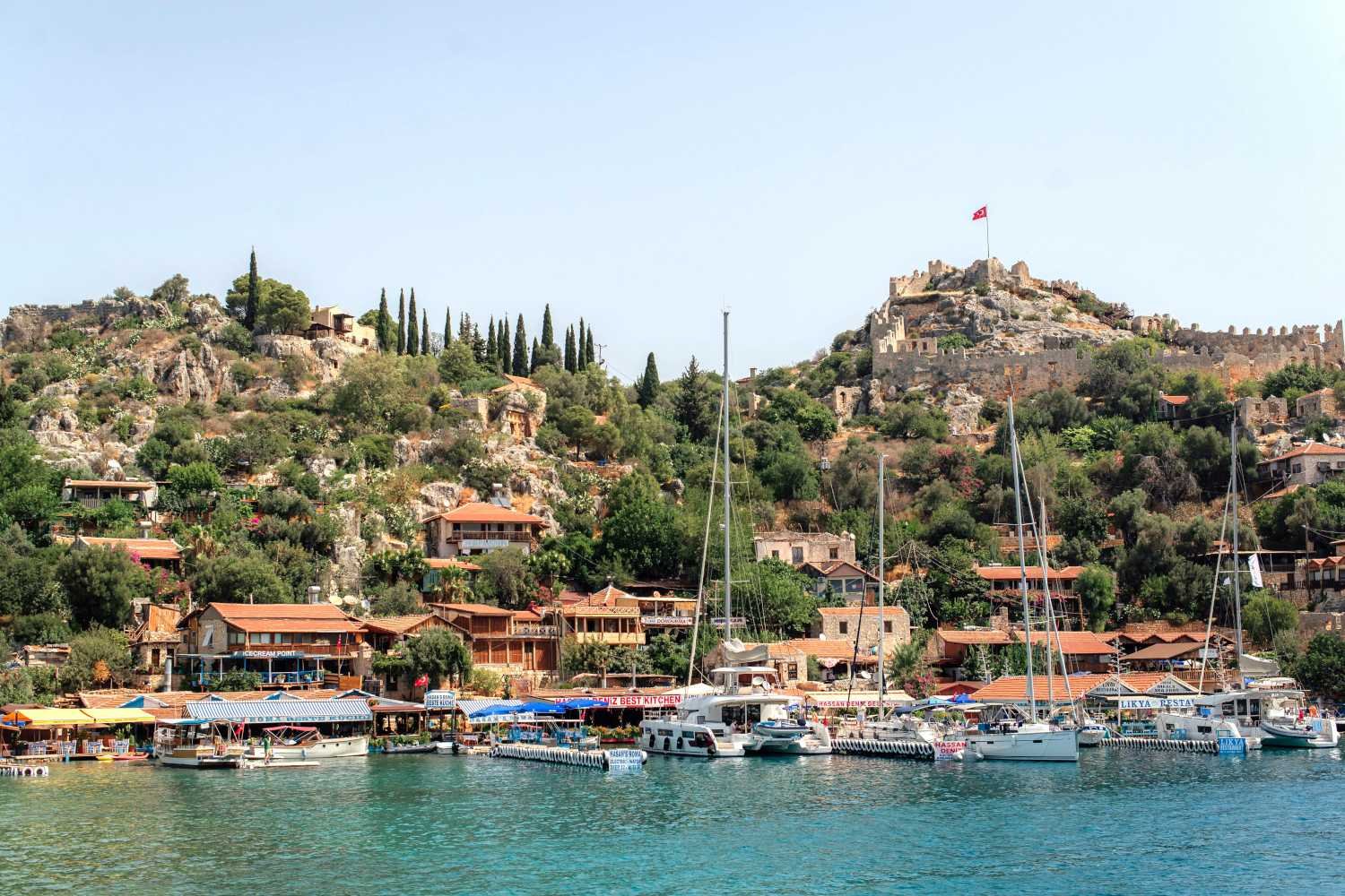 Kekova hillside village with fortress, turquoise waterfront and boats near Kalkan.