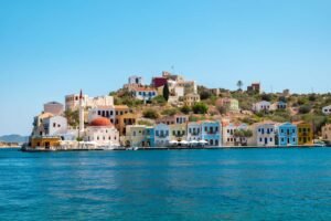Colourful Meis island waterfront with bright houses, red‑domed building and calm blue sea near Kalkan.