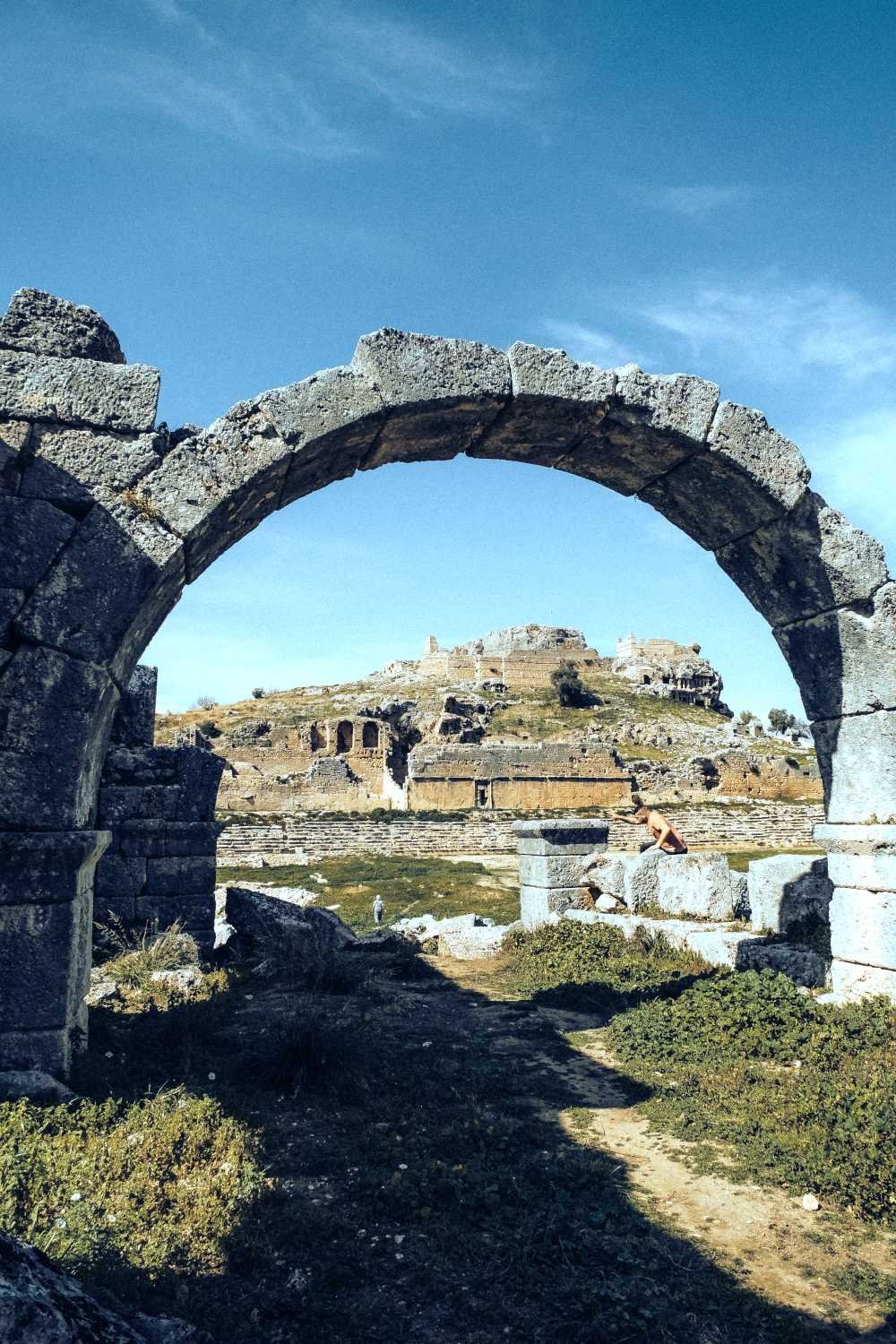 Ancient stone archway at Tlos framing hillside ruins and historic Lycian structures near Kalkan.