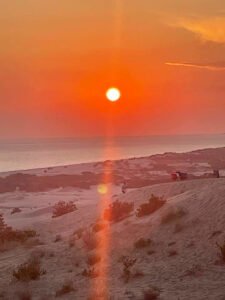 Sunset over a sandy beach near Kalkan with warm orange skies and gentle coastal dunes.
