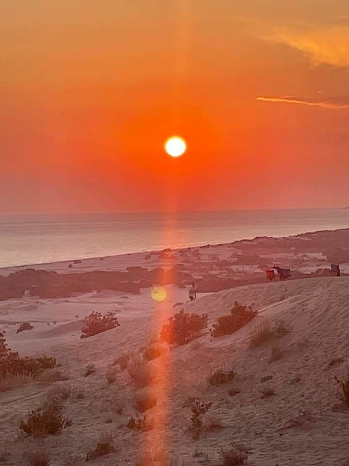 Sunset over a sandy beach near Kalkan with warm orange skies and gentle coastal dunes.