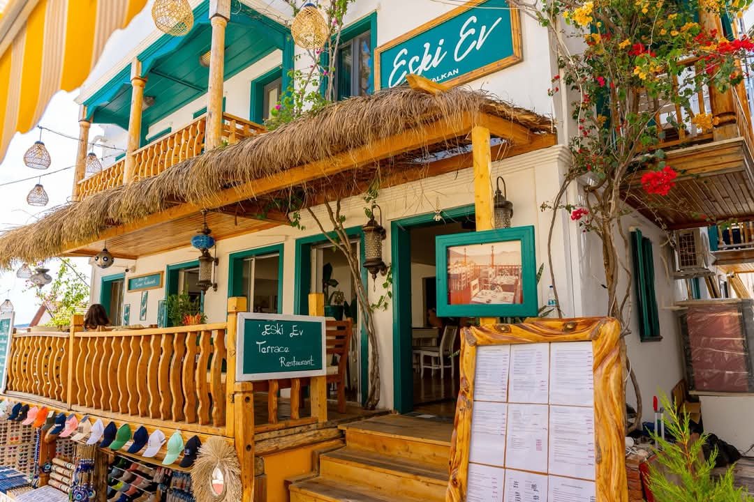 Eski Ev Terrace Restaurant in Kalkan with rustic wooden features, turquoise trim and vibrant flowers.