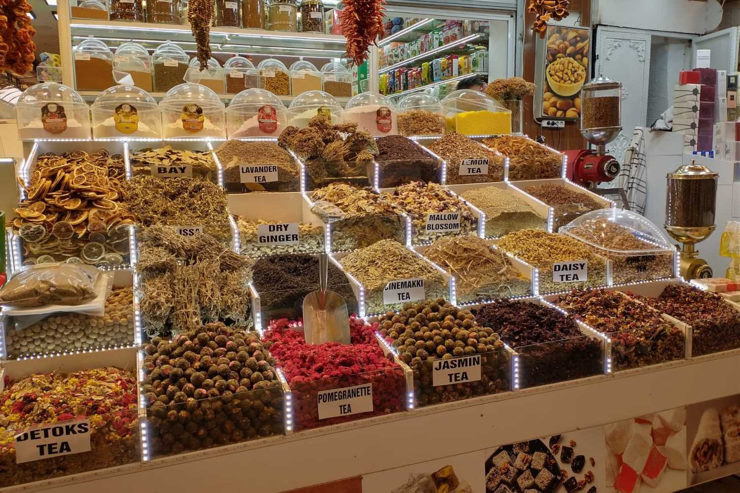 Display of dried herbs, teas and spices in a Kalkan shop with labelled compartments and jars.