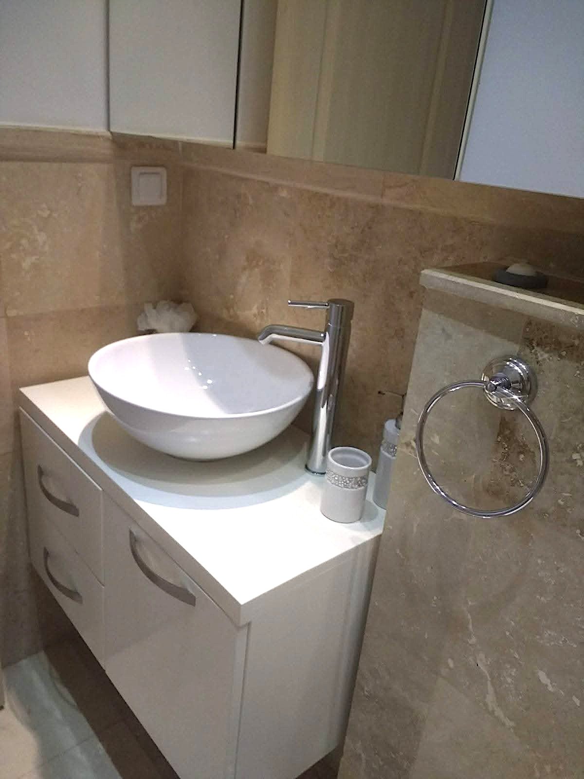 Modern bathroom sink at Kalkan Limon Apartment with vessel basin, marble tiles and mirrored cabinets.