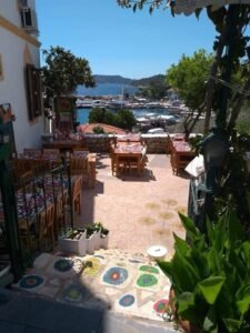 Terrace restaurant in Kaş overlooking the harbour with colourful décor, wooden tables and sea views.