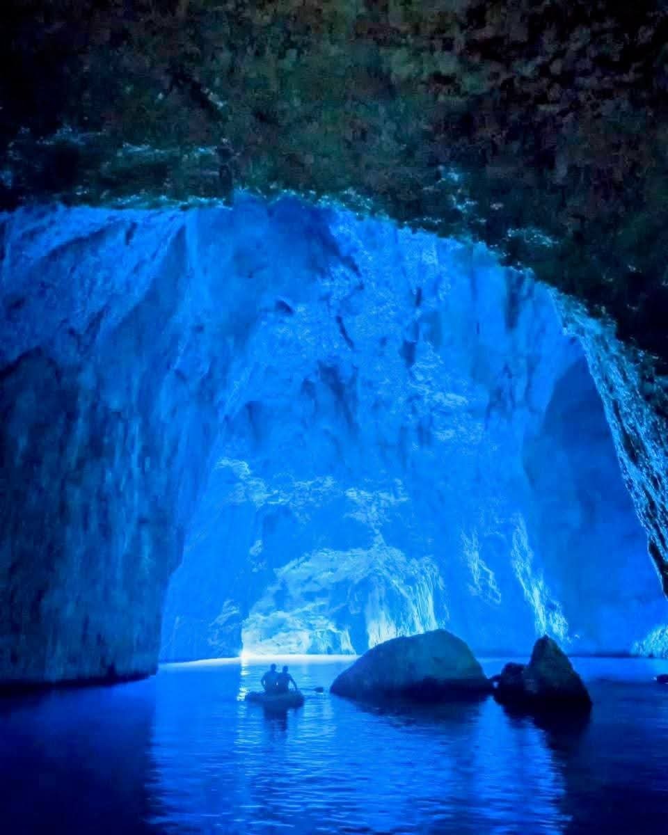 Blue Cave in Meis with vivid blue water and a small boat inside the illuminated sea cavern.